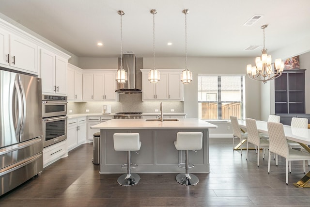 kitchen with a sink, backsplash, stainless steel appliances, wall chimney exhaust hood, and light countertops