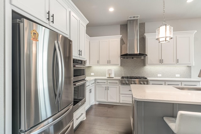 kitchen with visible vents, backsplash, appliances with stainless steel finishes, wall chimney exhaust hood, and a sink