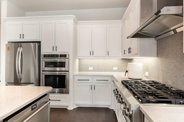 kitchen with under cabinet range hood, backsplash, appliances with stainless steel finishes, and white cabinetry