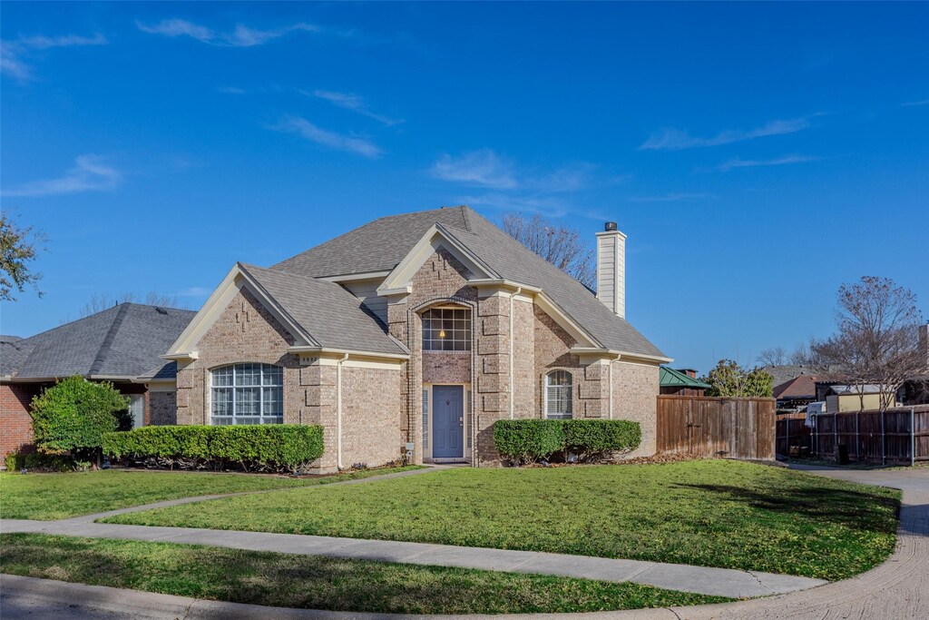 9908 Carmel Valley Dr, Frisco, TX 75035 - french country style house with a front lawn, fence, a shingled roof, brick siding, and a chimney