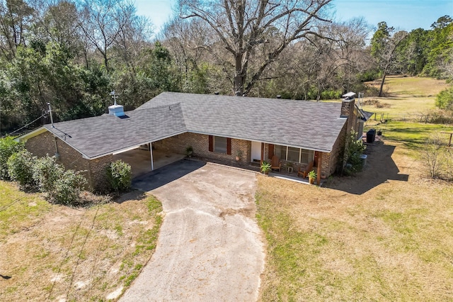 view of front of home with brick siding, concrete driveway, a front yard, a chimney, and a carport