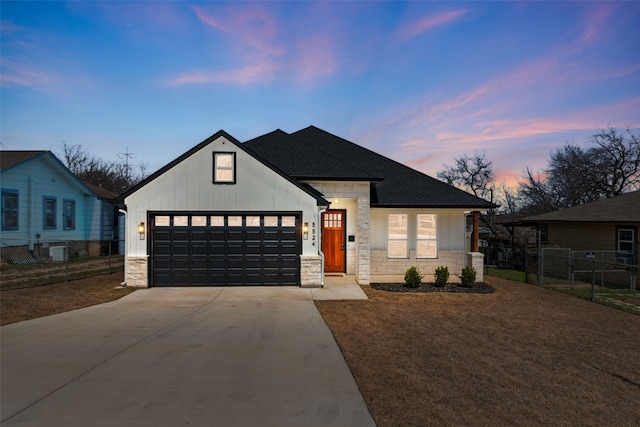 view of front of house featuring driveway, stone siding, fence, board and batten siding, and a garage