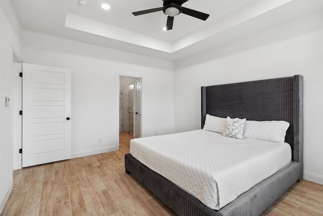 bedroom featuring baseboards, ceiling fan, light wood-type flooring, recessed lighting, and a raised ceiling