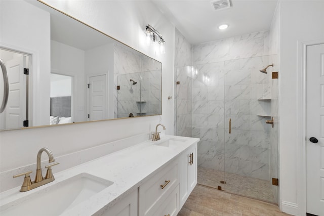 bathroom with a marble finish shower, visible vents, double vanity, and a sink