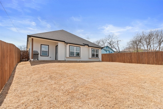 view of front facade with a fenced backyard and a shingled roof