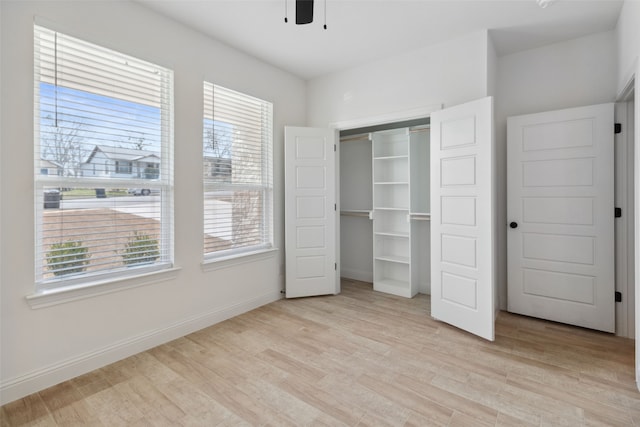 unfurnished bedroom featuring light wood-style floors, baseboards, a closet, and ceiling fan