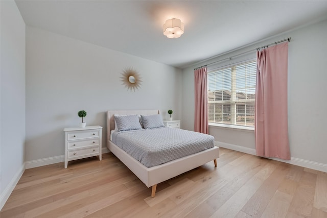 bedroom featuring light wood finished floors and baseboards