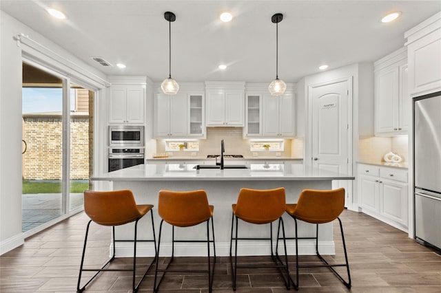 kitchen with a sink, stainless steel appliances, a breakfast bar area, and white cabinets