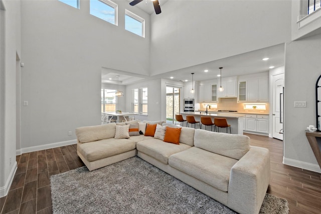 living area featuring wood finish floors, plenty of natural light, baseboards, and ceiling fan