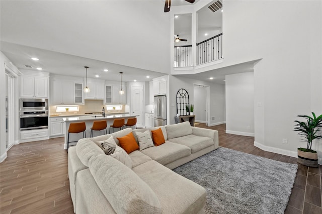 living area with baseboards, visible vents, light wood finished floors, recessed lighting, and ceiling fan