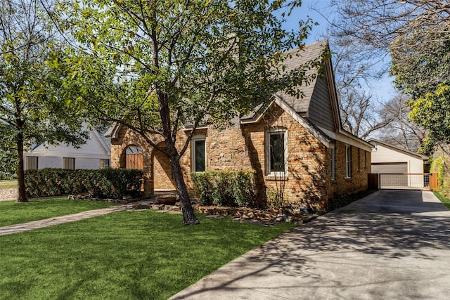 view of front of home with an outbuilding, brick siding, a front yard, and a detached garage