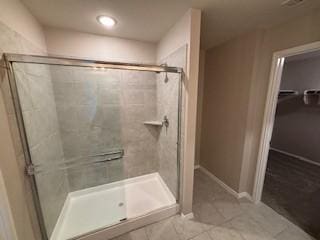 full bath featuring baseboards, a stall shower, a spacious closet, and tile patterned flooring