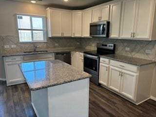 kitchen with a sink, dark wood-style floors, a kitchen island, and stainless steel appliances