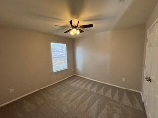 empty room featuring dark colored carpet, baseboards, and ceiling fan