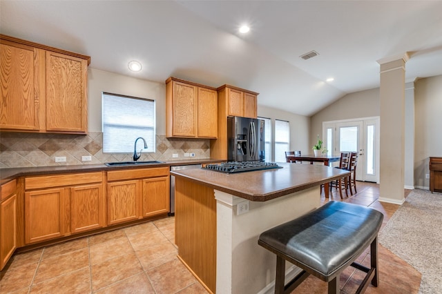 kitchen featuring visible vents, a sink, vaulted ceiling, a kitchen bar, and refrigerator with ice dispenser