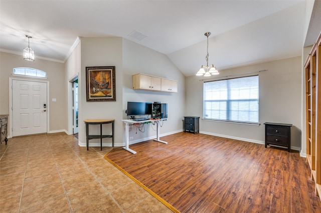 unfurnished living room featuring wood finished floors, visible vents, baseboards, lofted ceiling, and a chandelier