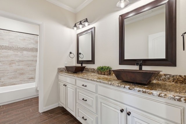 full bath with a sink, wood tiled floor, double vanity, and crown molding