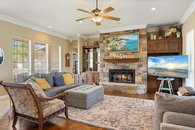 living area featuring recessed lighting, a stone fireplace, wood finished floors, a ceiling fan, and ornamental molding