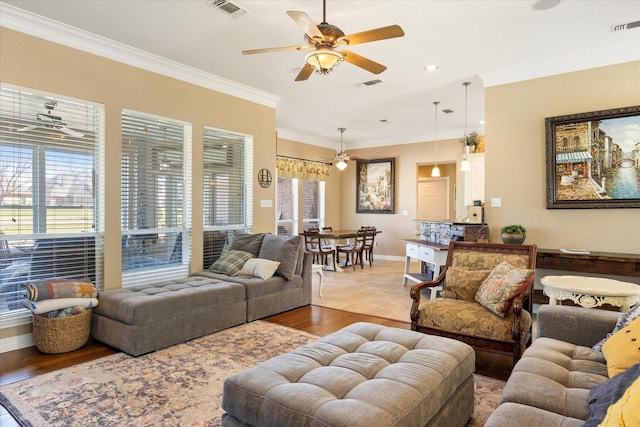 living room featuring wood finished floors, visible vents, a ceiling fan, and ornamental molding