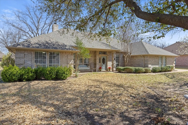 view of front of home with a chimney and brick siding