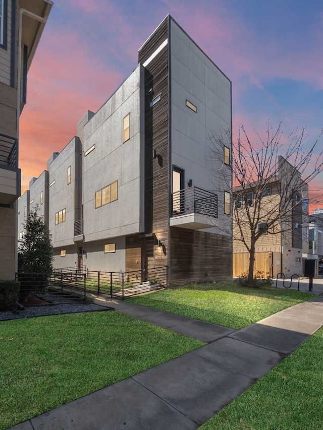 view of side of property with stucco siding, a yard, and fence