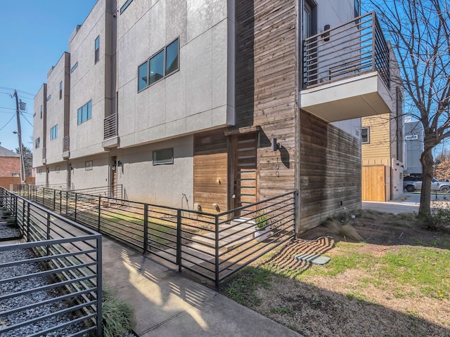 view of side of home with stucco siding and a balcony