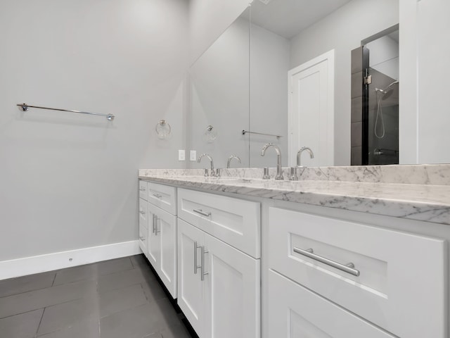 bathroom with double vanity, baseboards, a shower, and a sink