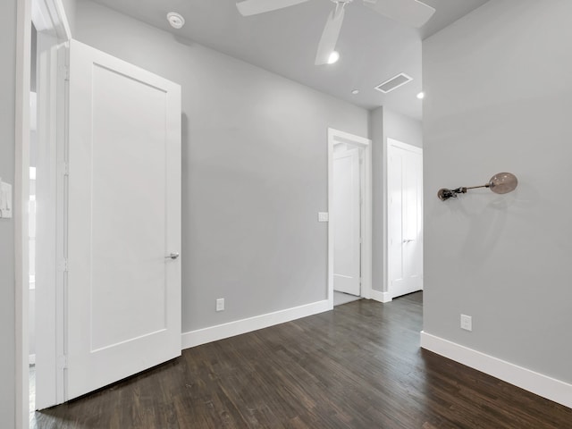 spare room featuring visible vents, ceiling fan, dark wood-type flooring, and baseboards