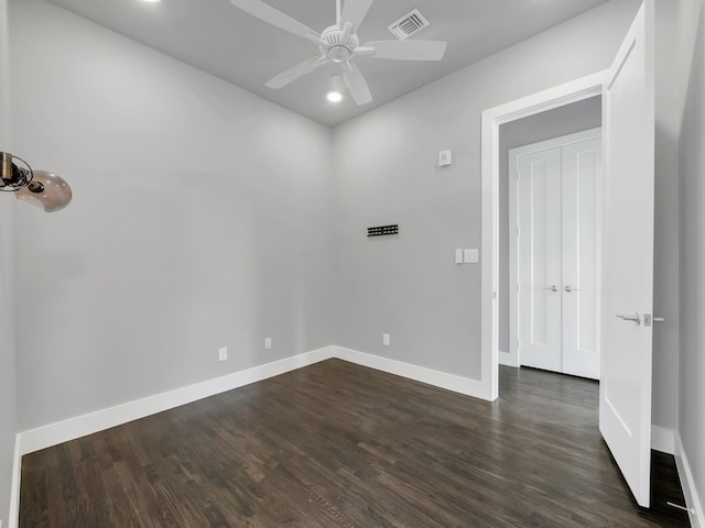 spare room with baseboards, dark wood-style flooring, and ceiling fan