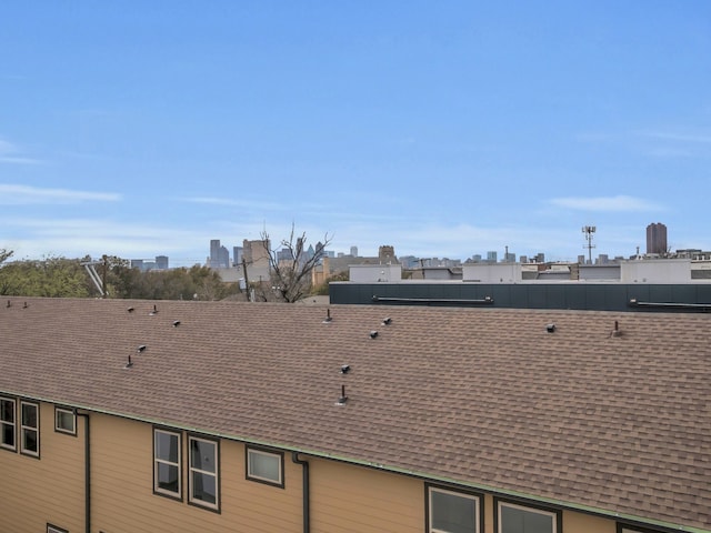 details with a city view, roof with shingles, and a downspout