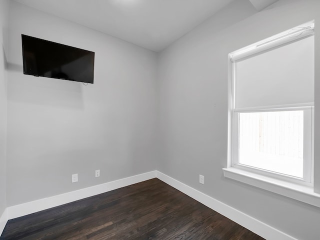 unfurnished room with baseboards and dark wood-type flooring