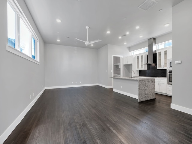 unfurnished living room with a ceiling fan, baseboards, visible vents, dark wood-style flooring, and a sink