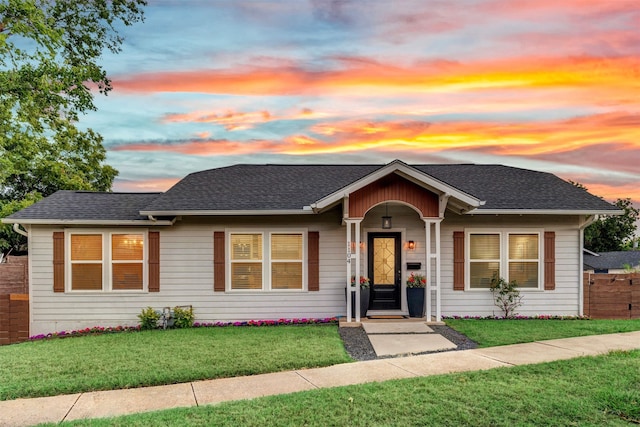 single story home featuring a shingled roof, a yard, and fence