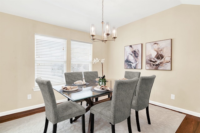 dining space with lofted ceiling, wood finished floors, baseboards, and a chandelier