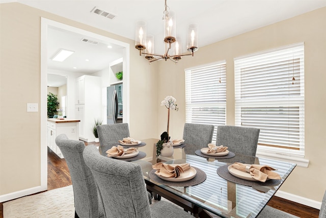 dining space featuring wood finished floors, visible vents, and a chandelier