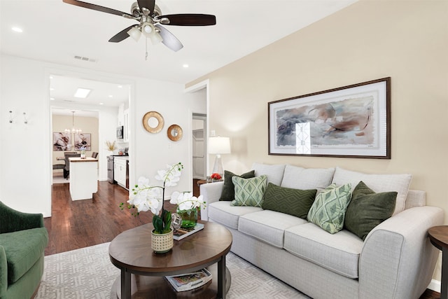 living area featuring recessed lighting, visible vents, dark wood-style flooring, and ceiling fan with notable chandelier