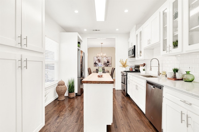 kitchen featuring visible vents, a sink, a kitchen island, appliances with stainless steel finishes, and decorative backsplash