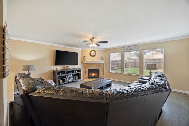 living area featuring a lit fireplace, ornamental molding, a ceiling fan, and wood finished floors