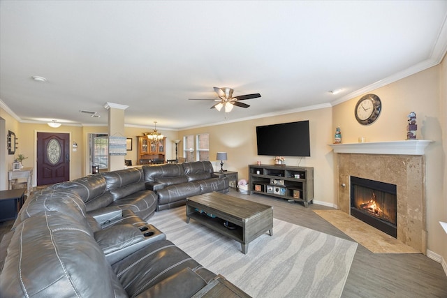 living area with visible vents, ornamental molding, ceiling fan with notable chandelier, wood finished floors, and a fireplace