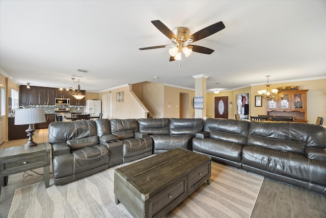 living area with light wood-style floors, ceiling fan with notable chandelier, visible vents, and ornamental molding