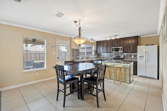 dining space featuring light tile patterned flooring, visible vents, crown molding, and baseboards