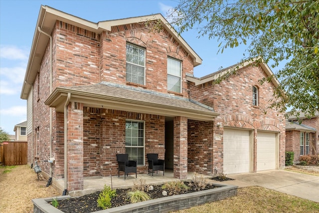 traditional home featuring a garage, brick siding, driveway, and fence