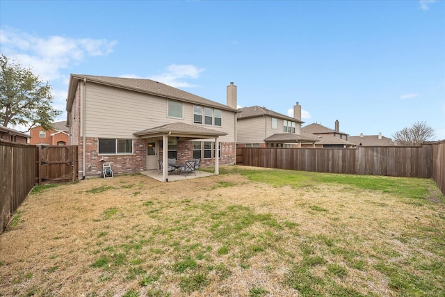 rear view of house featuring a lawn, a fenced backyard, brick siding, and a patio area