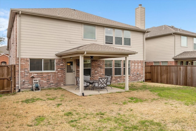 rear view of property featuring a patio, brick siding, and a fenced backyard