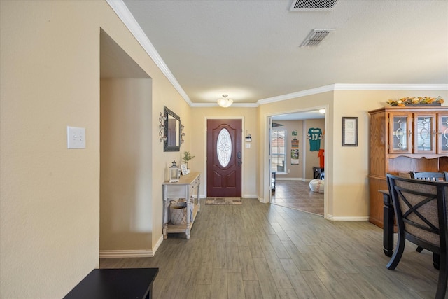 entryway featuring visible vents, crown molding, baseboards, and wood finished floors