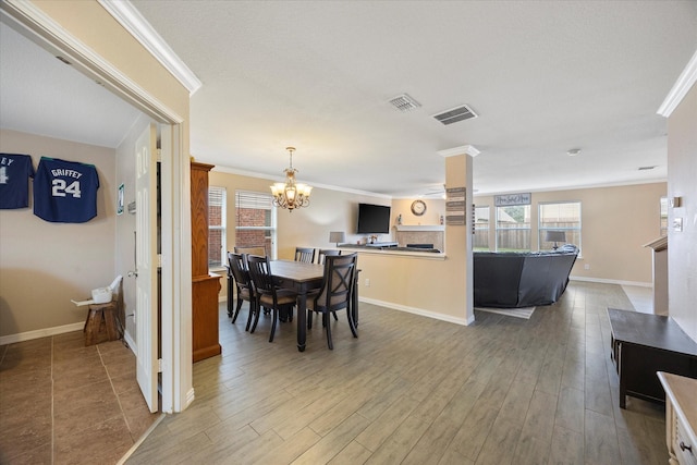 dining room featuring crown molding, wood finished floors, visible vents, and a chandelier