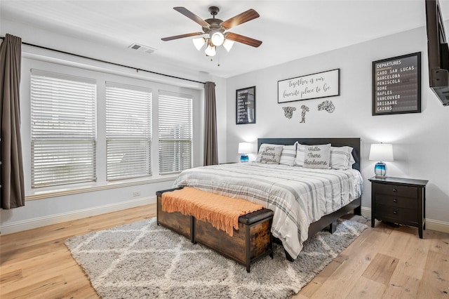 bedroom featuring a ceiling fan, visible vents, wood finished floors, and baseboards