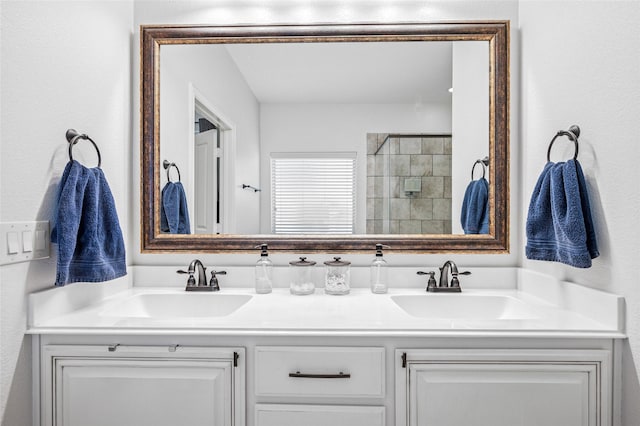 full bath featuring double vanity, tiled shower, and a sink