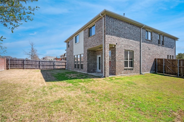 rear view of property featuring a fenced backyard, brick siding, and a yard