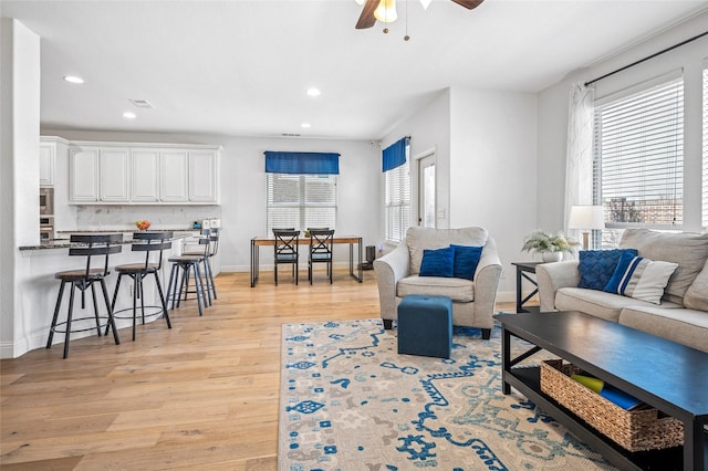 living area with a ceiling fan, visible vents, baseboards, recessed lighting, and light wood-type flooring